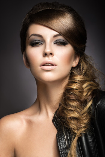Beautiful girl with bright make-up, perfect skin and hairstyle as a braid.Picture taken in the studio on a gray background